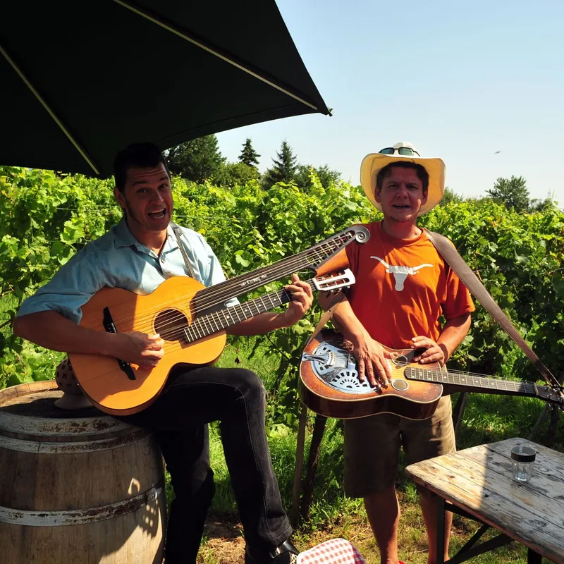 Zwei Musiker spielen Gitarre neben einem Weinfass