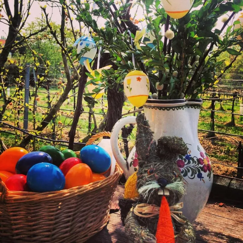 Ostereier im Korb, Osterstrauß im Krug und ein Strohhase vor dem Weingarten